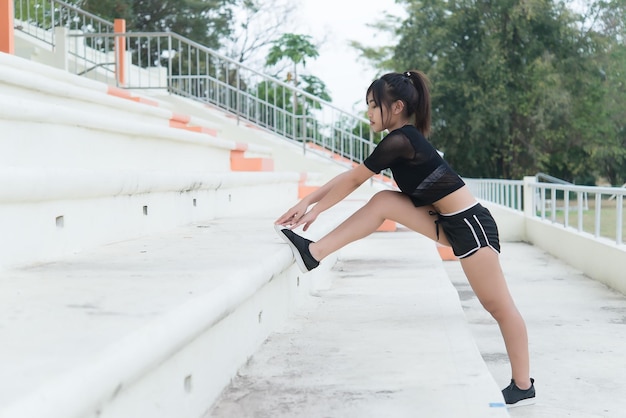 Красивая азиатская женщина растягивает тело на лестнице