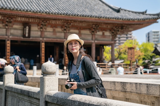 일본의 유명한 전통 사원에 있는 다리에서 사진을 찍는 아름다운 아시아 여성.