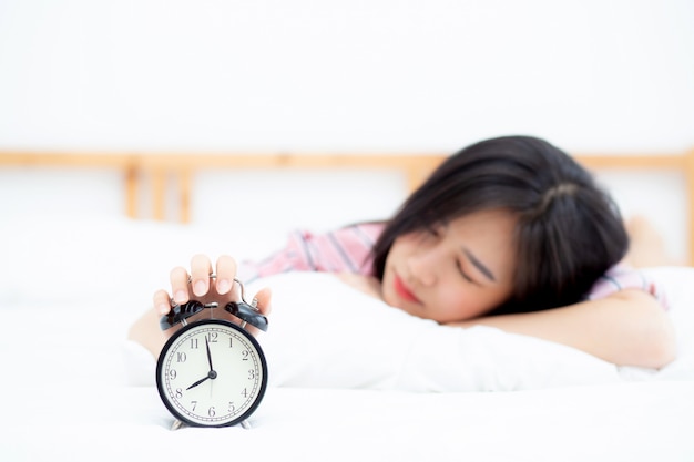 Beautiful asian woman turn off alarm clock in morning