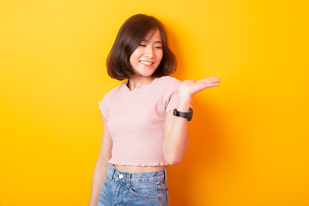 Beautiful asian woman university student happy on yellow wall