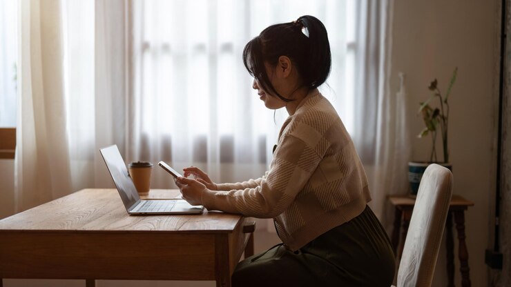Photo 一位美麗的亞洲女人在咖啡廳遠程工作時使用她的智能手機回應訊息