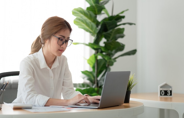 Beautiful asian woman using laptop computer at home office.