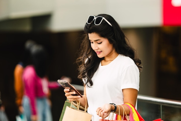 Beautiful asian woman using smart phone with shopping bag in the city