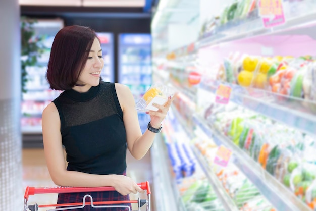 Beautiful asian woman walking shopping in a supermarketTime for relaxBuy for dinnerThailand peopleHappy time lifestyle concept