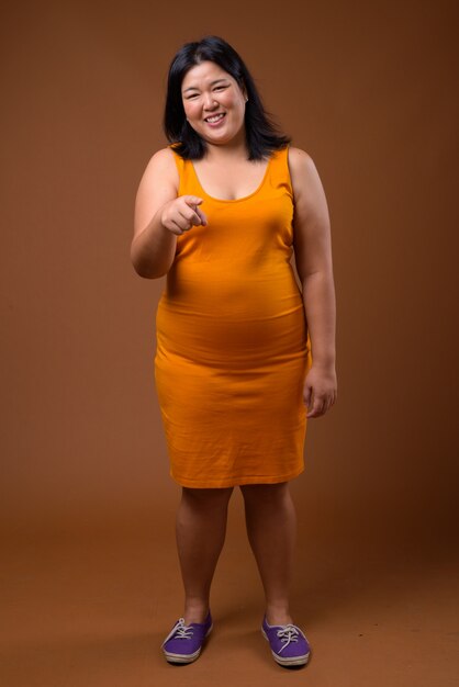 갈색에 주황색 민소매 드레스를 입고 아름다운 아시아 여자