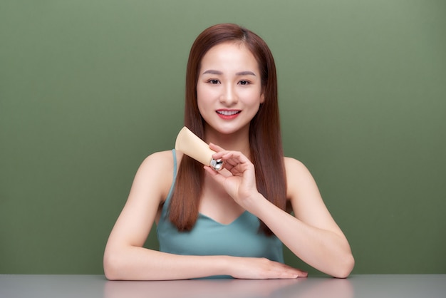 Beautiful Asian Woman with healthy skin concept, holding skin cream blank tube package