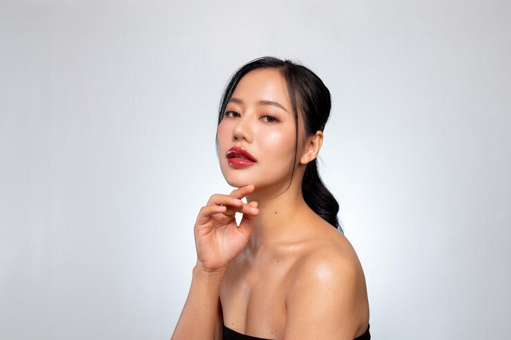 Photo a beautiful asian woman with perfect makeup and tanned skin poses against a grey studio background