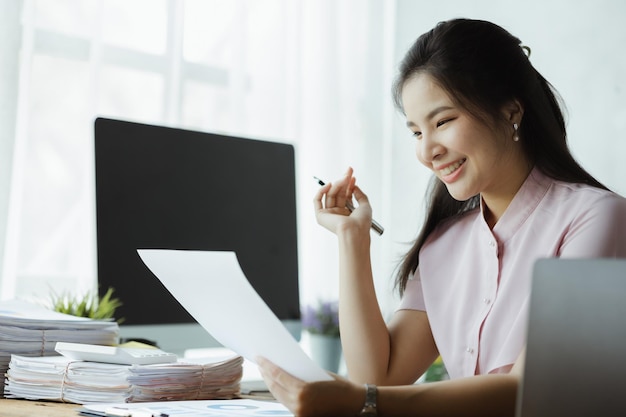 Beautiful asian woman working with computers in the office of a
startup company she is a company finance employee working in the
finance department concept of women working in a company