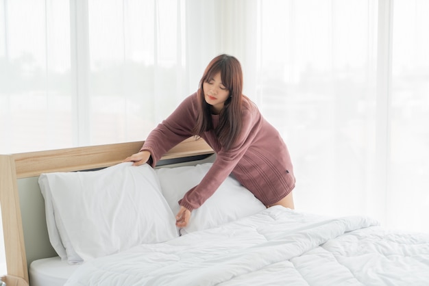 beautiful Asian women making bed in room with white clean sheet