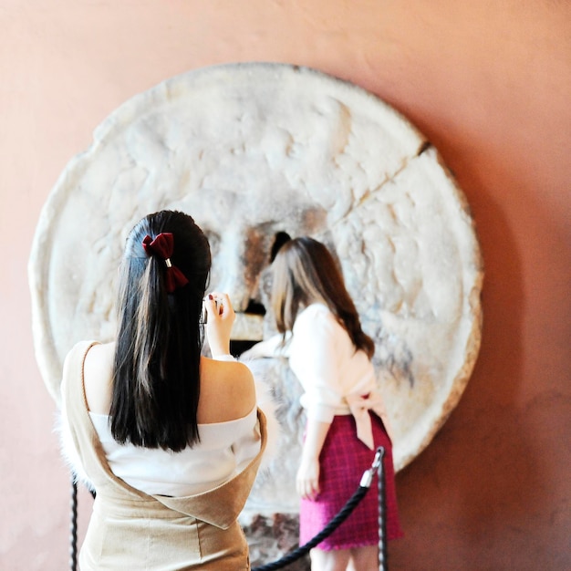 Beautiful asian women photograph each other in front of the mouth of truth Bocca della Verita Church of Santa Maria in Cosmedin in Rome Italy