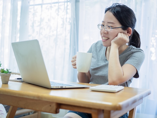 Beautiful asian women working at home and team conferencing using notebook