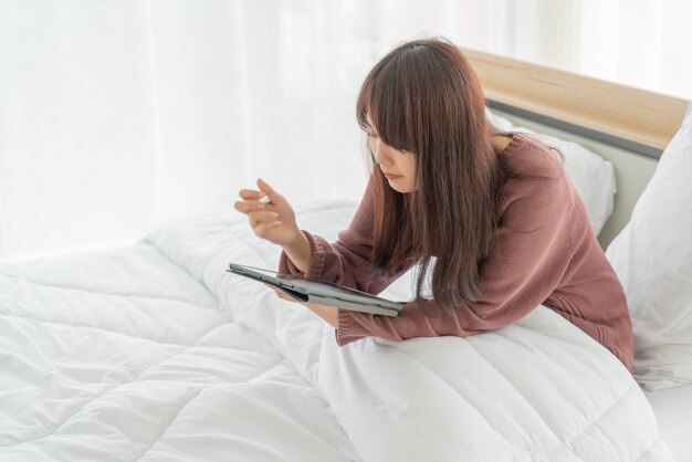 beautiful Asian women working with tablet on bed