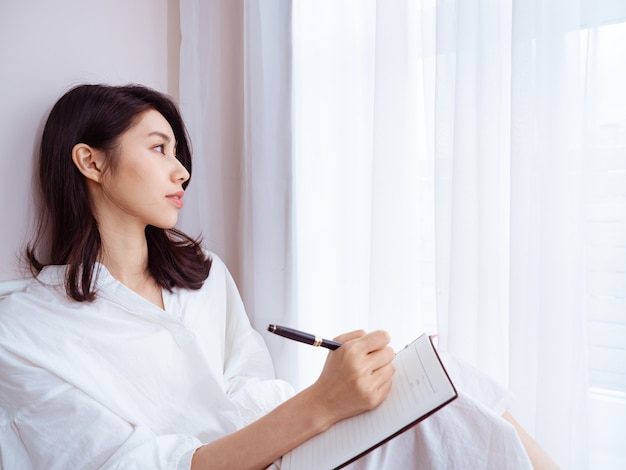 A beautiful Asian women writes something in a book