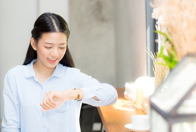 Beautiful asian young woman look at watch waiting for friend or someone.