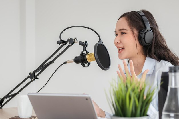 아름다운 아시아 젊은 여성 라디오 진행자는 헤드폰, 마이크, 대화, 녹음 팟캐스트, 소셜 미디어에서 생중계합니다. 스튜디오에서 방송하는 온라인 방송 기술.