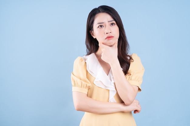 Beautiful Asian young woman wearing yellow dress on blue blackground