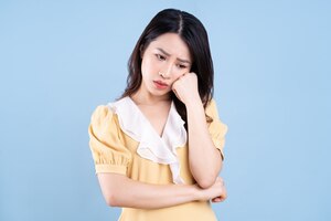 Beautiful asian young woman wearing yellow dress on blue blackground