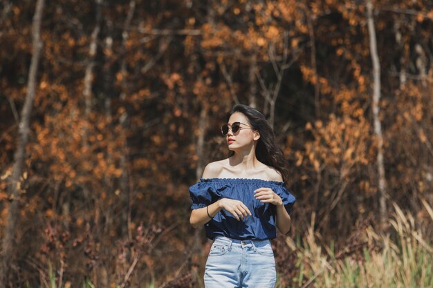 Beautiful asian younger woman standing aginst dry leaves forest