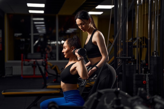 Beautiful athlete woman exercising with dumbells in fitness club