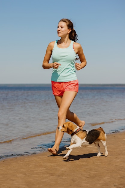 A beautiful and athletic european girl does sports in nature\
with her dog fitness and yoga in the