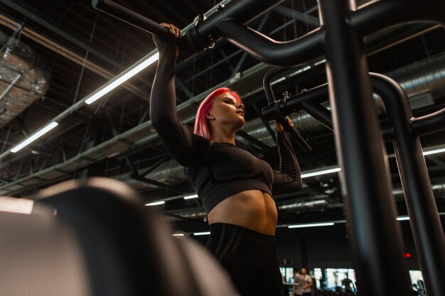 Beautiful athletic girl doing workout and pulling herself up in the gym