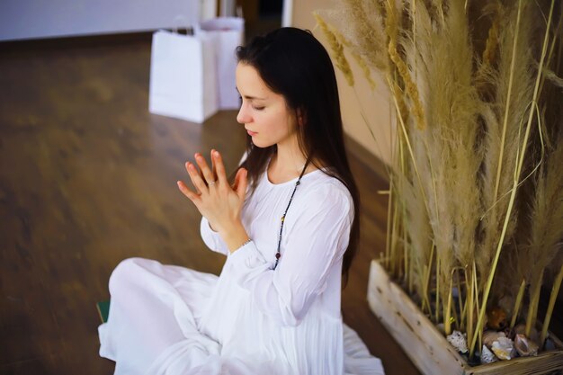 Beautiful athletic girl doing yoga exercises enjoy meditation\
at home. no stress, healthy habit, anxiety relief concept. lotus\
pose.