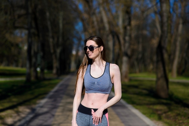 Beautiful athletic girl in sport clothes and glasses on the playground. Healthy lifestyle. Soft selective focus.