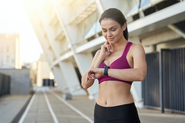 Beautiful athletic lady is using smartwatch outdoor