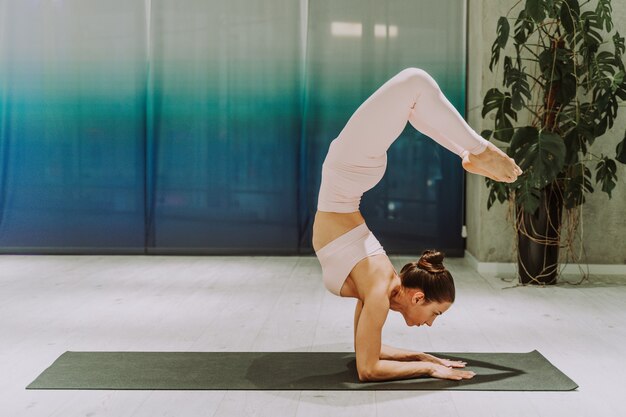 Beautiful athletic woman training in a gym, doing stretching exercises before the workout 