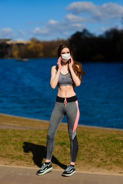 Beautiful athletic woman with a mask in the park