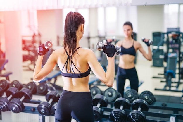 Beautiful athletic young woman making exercise at the gym Young woman with muscular body Fitness concept