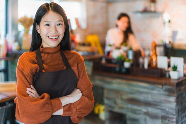 Beautiful attractive asian cafe shop owner smile with happiness and joyful with coffee cup apron cafe background