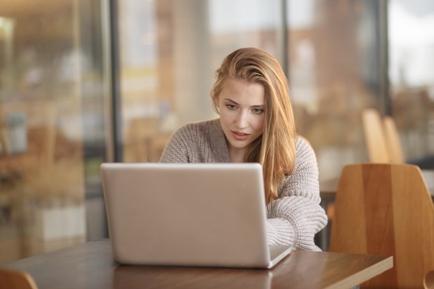 Beautiful attractive girl working in a coffe shop with a laptop