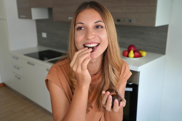 Beautiful attractive healthy woman eating dried fruit at home