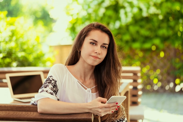 Bella donna attraente al caffè con un computer portatile con una pausa caffè