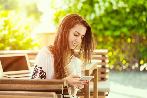 コーヒーブレークを持つラップトップとカフェで美しい魅力的な女性