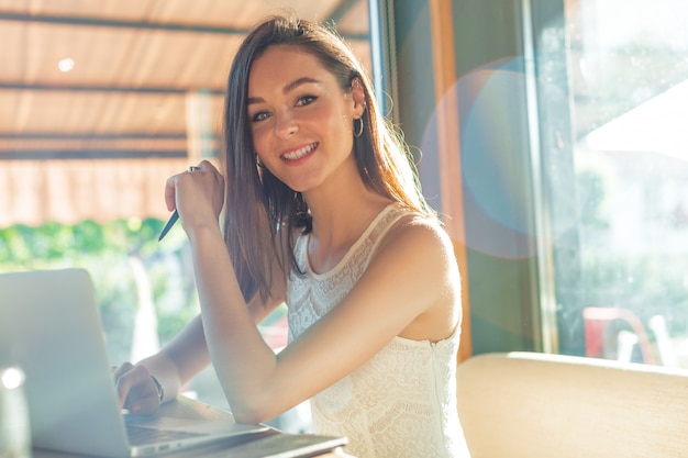 コーヒーブレークを持つラップトップでカフェで美しい魅力的な女性