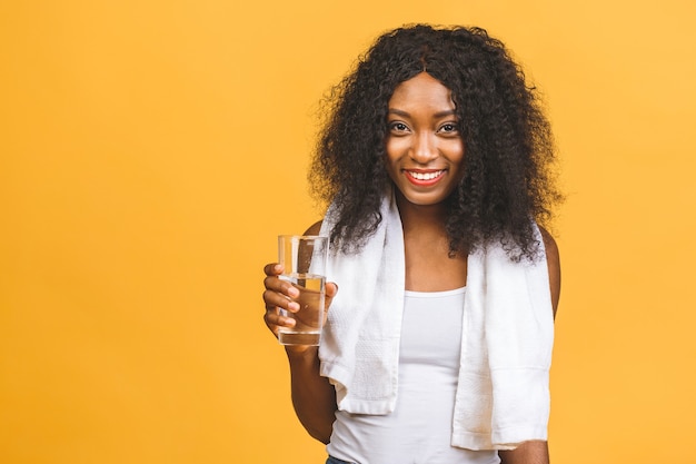 Красивая привлекательная молодая потная афро-американская черная женщина пьет воду после тренировки