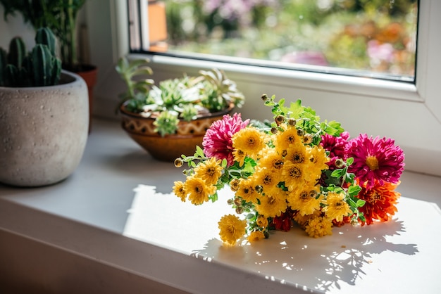 창턱에 노란 아스터와 국화 꽃의 아름다운 가을 꽃다발 | 프리미엄 사진