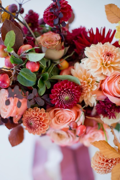 Beautiful autumn bouquet with orange and red flowers and berries Autumn bouquet with ribbons on a white background