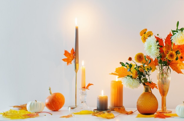 Beautiful autumn home decor with burning candles in white interior