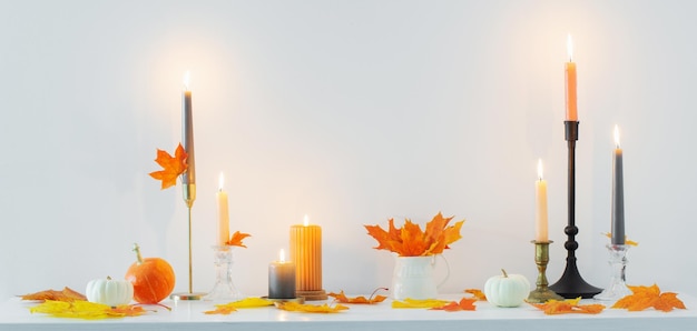 Beautiful autumn home decor with burning candles in white interior