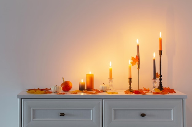 Beautiful autumn home decor with burning candles in white interior