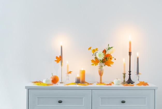 Красивый осенний домашний декор с зажженными свечами в белом интерьере