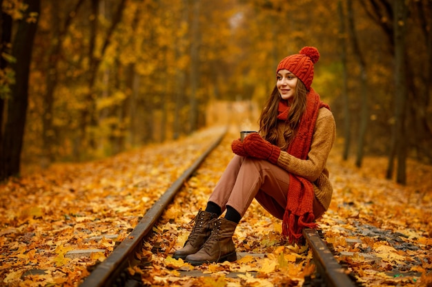 Beautiful autumn portrait of woman in forest or park with orange fall foliage on blurred background