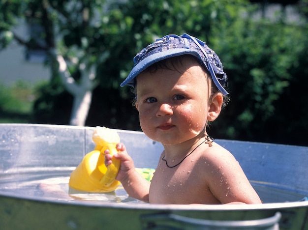 Красивый мальчик в детской ванне позирует фотографу для цветного фото Кадр, состоящий из мальчика