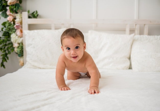 Bellissimo bambino in un pannolino striscia a quattro zampe sul letto