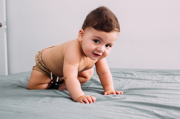 Beautiful baby crawling on the bed in the room, family lifestyle