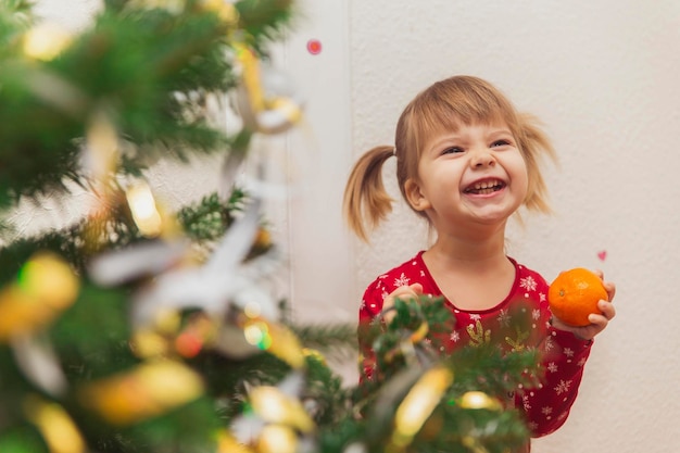 Beautiful baby grimaces near the Christmas tree