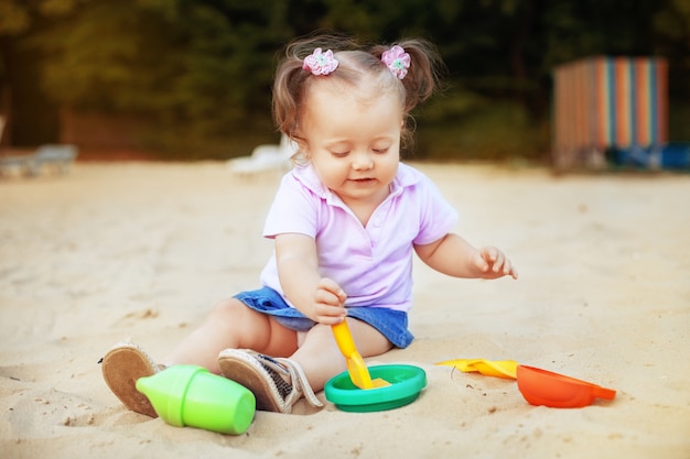 サンドボックスのおもちゃで遊ぶ美しい赤ちゃん。幼年期および開発。